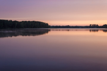 Fototapeta na wymiar Sunrise over the forest lake. Reflection of the sky in the lake. Summer