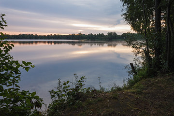 Naklejka na ściany i meble Sunrise over the forest lake. Reflection of the sky in the lake. Summer