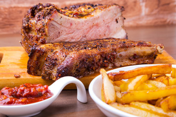 Grilled pork ribs with potato free and sauce on white plate.