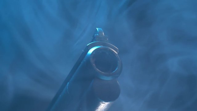 Camera making a closeup shot on the barrel of a revolver pistol gun. Smoke going around the object.