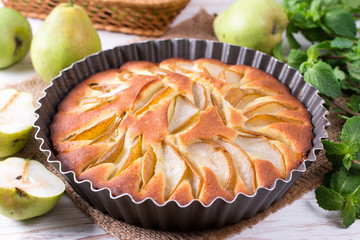 Homemade pear pie on a white table with pears