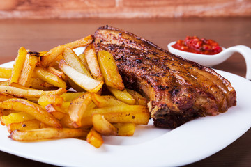 Grilled pork ribs with potato free and sauce on white plate.