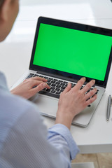 Over The Shoulder View Of Businesswoman Using Green Screen Laptop In Office
