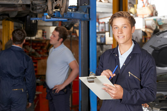 Portrait Of Apprentice Mechanic Holding Clipboard Working In Auto Repair Shop