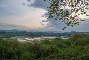 Landscape of marsh at sunset with vegetation and cloudy sky in San Vicente de la Barquera, Cantabria, Spain