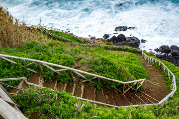 Walking trail along the sea, ladder with railing on the background of waves.