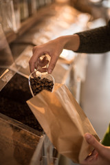 Obraz premium seller's hands filling a coffee bag from a bulk dispenser