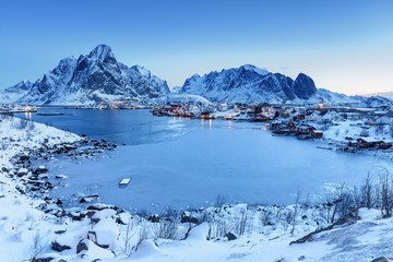 Fototapeta na wymiar Scenic view of historic village Reine on Lofoten Islands archipelago in Norway, Scandinavia. Picturesque twilight landscape of northern nature. Sophisticated snow-capped rocks in background.