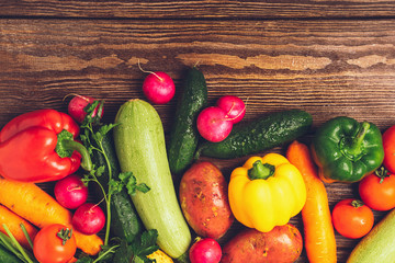 Fresh harvest ripe vegetables zucchini cucumber greens pepper laid out on a wooden background. Healthy food Harvesting.