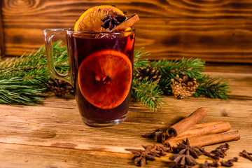 Cup of mulled wine with cinnamon and fir tree branches on wooden table