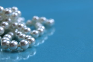 White pearl necklace lying on a blue background