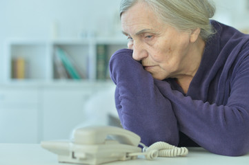 Obraz premium Portrait of a sad elderly woman looking at phone