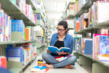 Asian women in library reading something in a book and choosing a book in a library.  Education  Concept