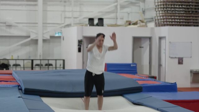 Man training on the trampoline at a gym in slow motion
