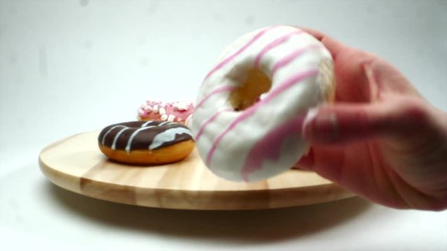 Commercial shot of yummy glazed donut in the hand, donuts set on the background