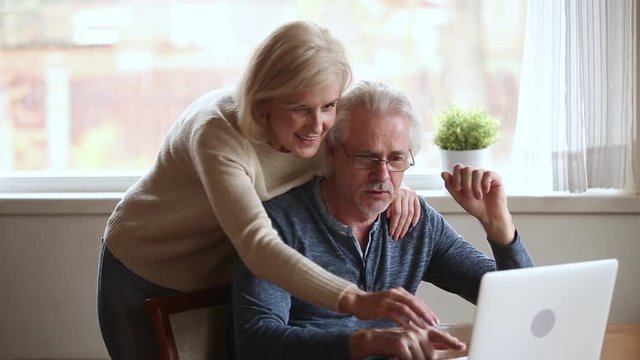 Elderly married couple internet users surfing web site at home