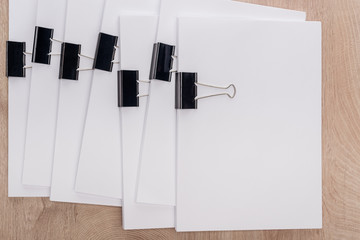 top view of stacks of blank paper with metal binder clips and copy space on wooden table