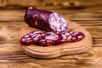 Cutting board with sliced salami sausage on a wooden table