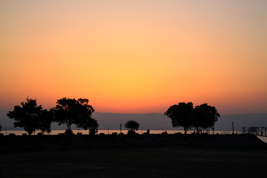 Stunning sunrise with silhouette of trees and tourists at Sea of Galilee © shellybychowskishots