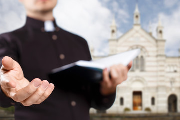 Young priest reading the Holy Bible and stretching his hand