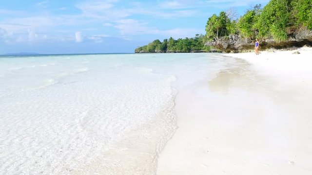 Slow motion: Woman sunbathing relaxing in turquoise water white sand beach tropical sea desert island Wakatobi Indonesia paradise travel destination sunny hot day