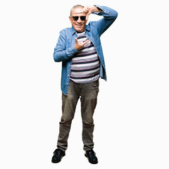 Fototapeta premium Handsome senior man wearing denim jacket and sunglasses smiling making frame with hands and fingers with happy face. Creativity and photography concept.