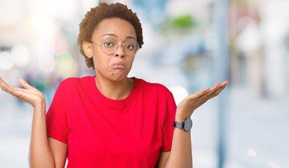 Beautiful young african american woman wearing glasses over isolated background clueless and...