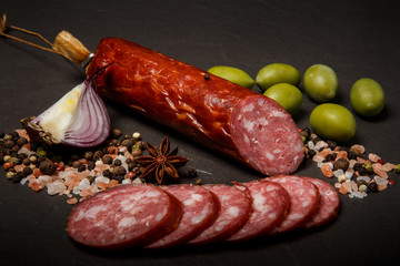 closeup dry cured salami sausage with onion and green olives