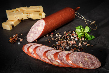 appetizing sliced cheddar summer sausage with cheese and basil