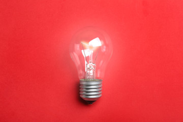 New modern lamp bulb on color background, top view