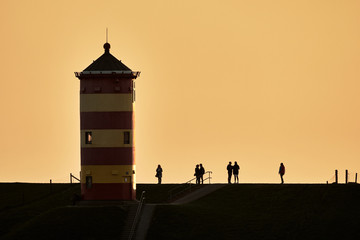 Pilsum lighthouse with silhouette of people at sunset in Germany