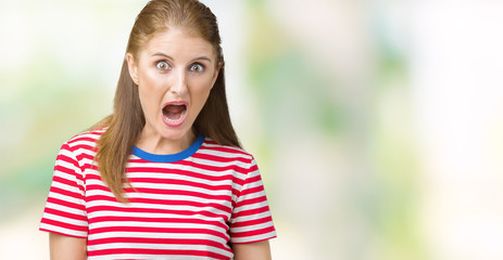 Middle age mature woman wearing casual t-shirt over isolated background In shock face, looking skeptical and sarcastic, surprised with open mouth