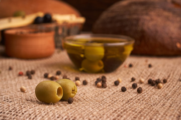 olive is on the table in background of bread, baguette and cheese. Selective focus