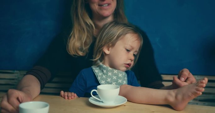 Mother and toddler drinking coffee at table