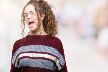 Beautiful brunette curly hair young girl wearing glasses over isolated background winking looking at the camera with sexy expression, cheerful and happy face.