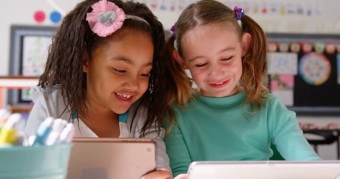 Front view of mixed-race schoolgirls studying on digital tablet in the classroom 4k