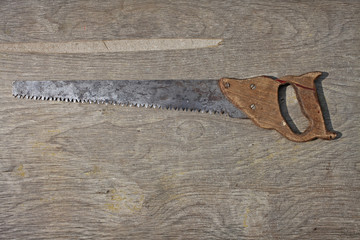 Old rusty saw on wooden background