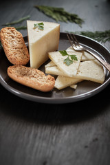 Sliced cured cheese and fork on gray plate