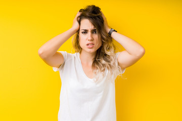 Young beautiful blonde woman over yellow background suffering from headache desperate and stressed because pain and migraine. Hands on head.