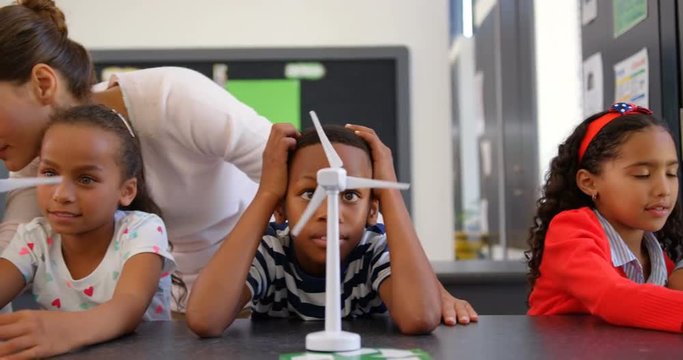 Front view of Caucasian female teacher teaching schoolkids about windmill in the classroom 4k