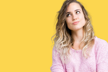 Fototapeta premium Beautiful young blonde woman over isolated background smiling looking side and staring away thinking.