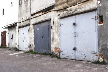 Garage cooperative. Rows of car garages. City architecture. Transport industry. Stone sheds. Rusty iron gate. Brick wall. Perspective in architecture. Abandoned area. Deserted street.