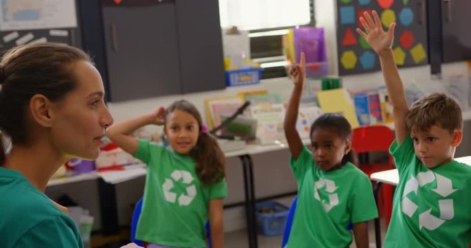 Side view of Caucasian female teacher teaching schoolkids about green energy and recycle in the clas