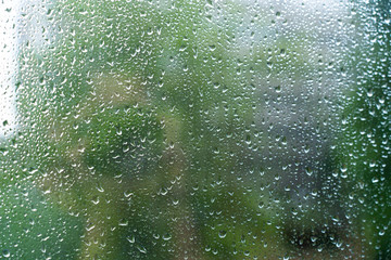 Drops of rain on glass with green background texture