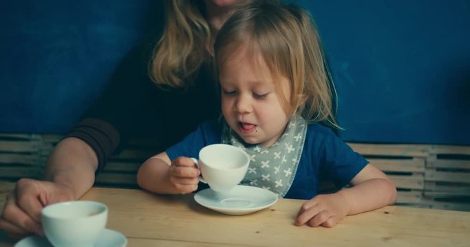 Mother and toddler drinkng coffee at table