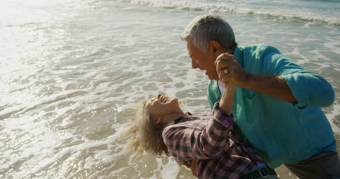 Side view of active senior Caucasian couple dancing together on the beach 4k