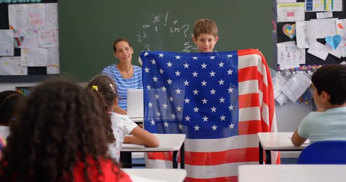 Front view of Caucasian schoolboy explaining about American flag in the classroom 4k