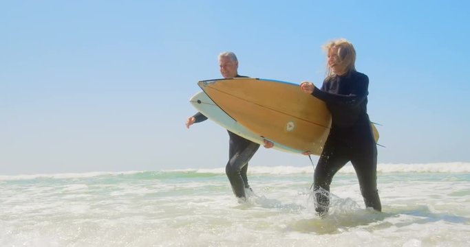 Front view of active senior Caucasian couple running on the sea at beach 4k