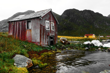 Old damaged and weathered wooden boat house at the coast of Vinstad on Lofoten Islands in Norway