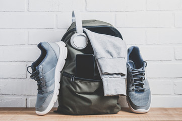 Green backpack with sportswear and sneakers. The concept of fitness or running